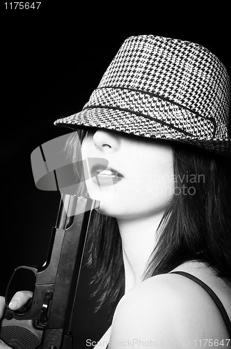 Image of Beautiful young girl in hat holding pistol in black and white