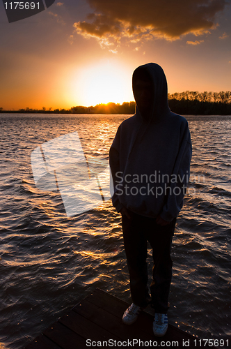 Image of Silhouette of a depressed man on the edge of a pier ready to jum