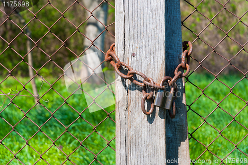 Image of Old padlock with chains onb wooden fence