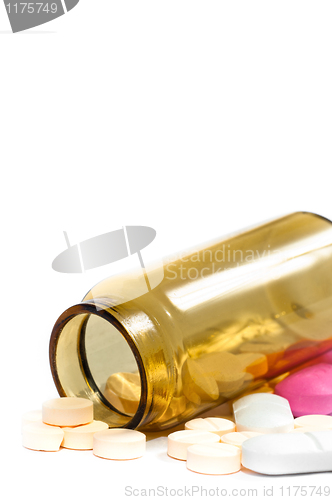 Image of Medicine bottle with purple and yellow pills against white isola