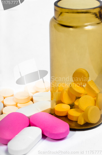 Image of Medicine bottle with purple and yellow pills against white isola