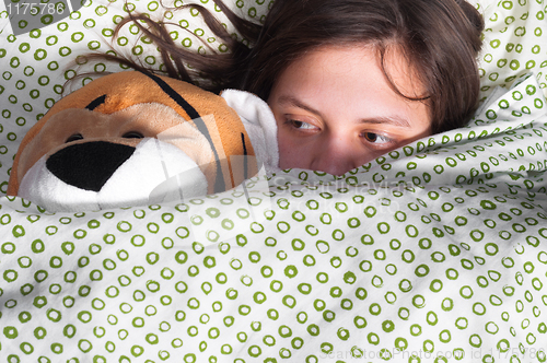 Image of young girl in bed holding teddy bear