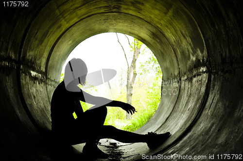 Image of Silhouette of a young girl smoking in sewer pipe