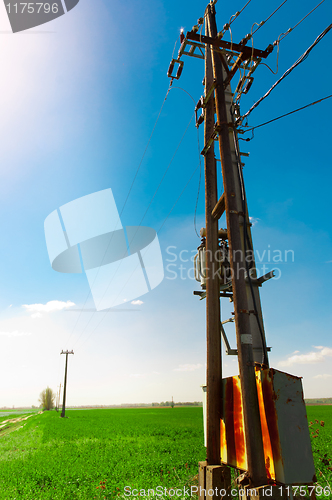 Image of Power line against blue sky on green field