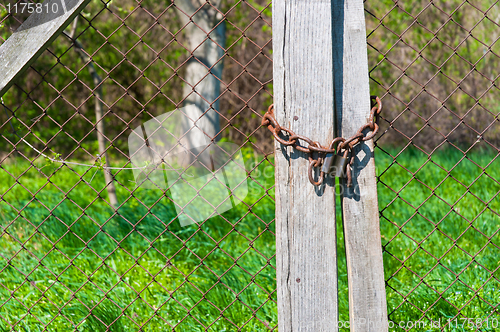 Image of Padlock on wooden fence with brigh green grass in background