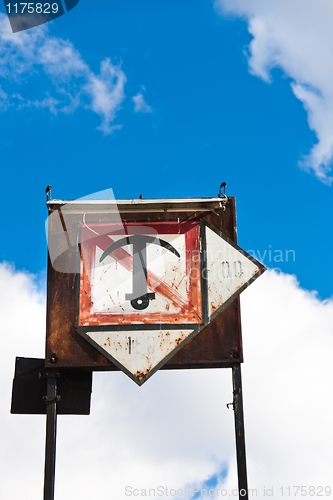 Image of Rusty sign with boat anchor against blue sky