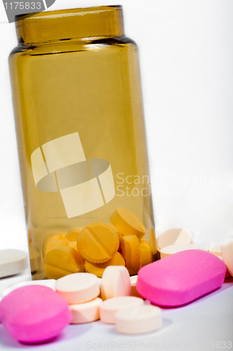 Image of Medicine bottle with purple and yellow pills against white isola