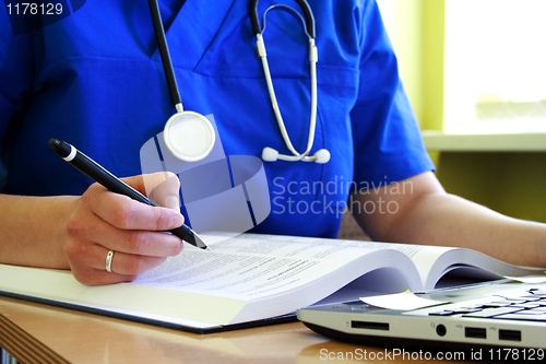 Image of medical doctor with stethoscope is writing