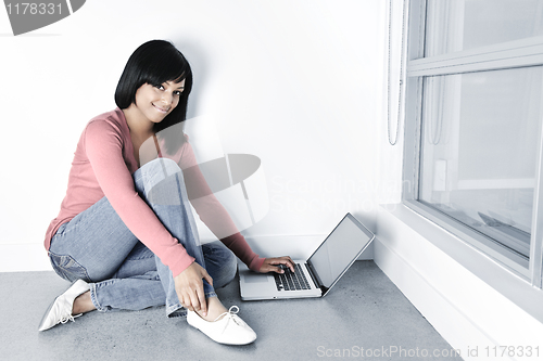 Image of Young woman using laptop computer on floor