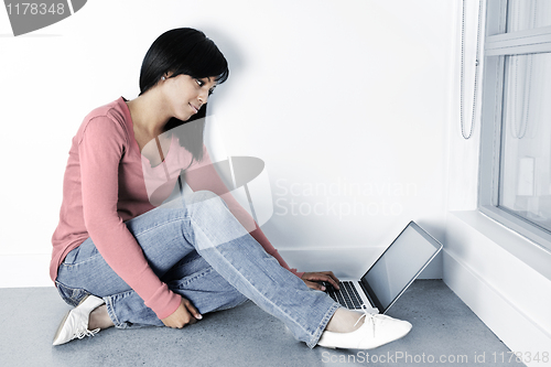 Image of Young woman using laptop computer on floor