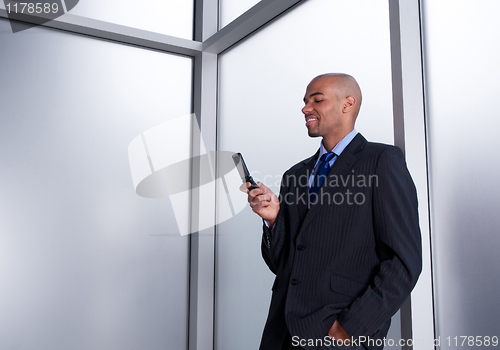 Image of Businessman beside a window looking at cell phone