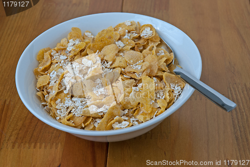 Image of White bowl with a spoon, corn and oats flakes