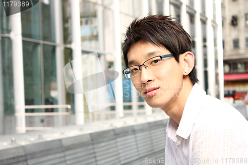 Image of businessman sitting on a bench in front of an office building 