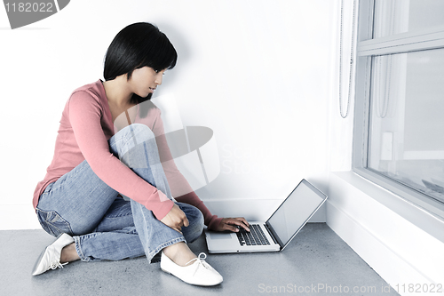Image of Young woman using laptop computer on floor