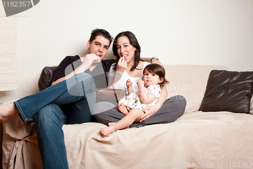 Image of Happy family snacking on sofa couch