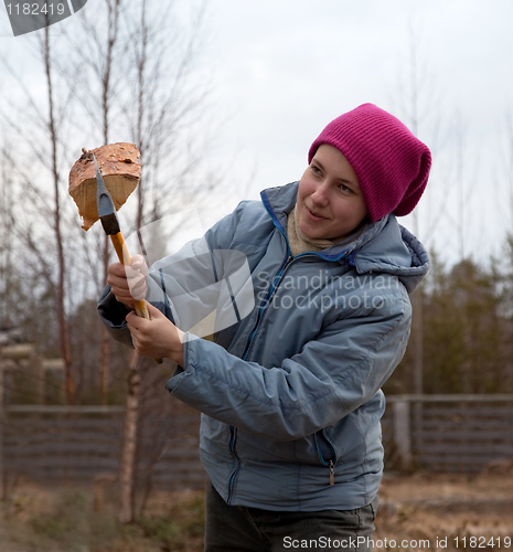 Image of Girl cuts firewood with an ax
