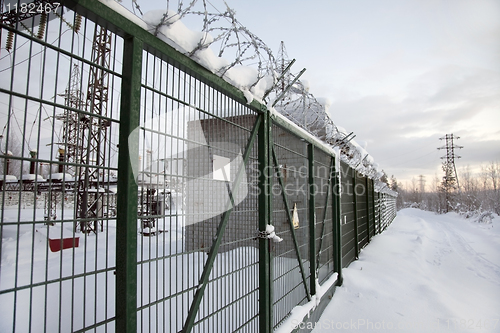 Image of electrical substation behind a fence topped with barbed wire