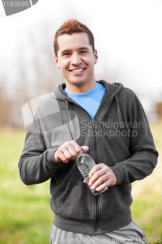 Image of Mixed race man holding water bottle