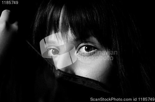 Image of Young arabic girl hiding her face with a scarf in black and whit