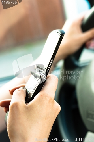 Image of A phone in the hand os a woman who is driveing 