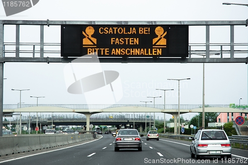 Image of Warning sign on highway with some cars on the road