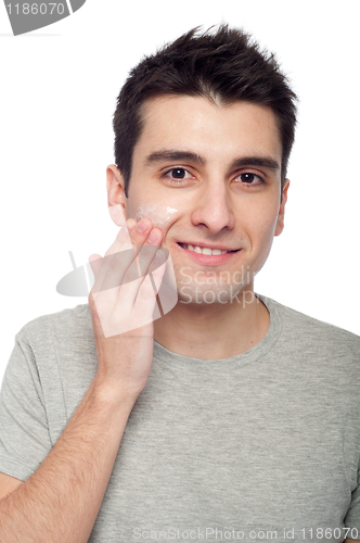 Image of Young man applying cream lotion