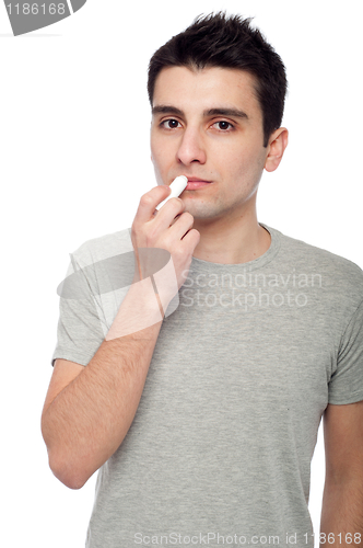 Image of Young man applying lip balm