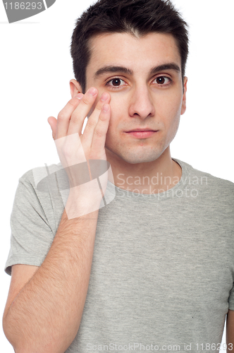 Image of Young man applying eye cream