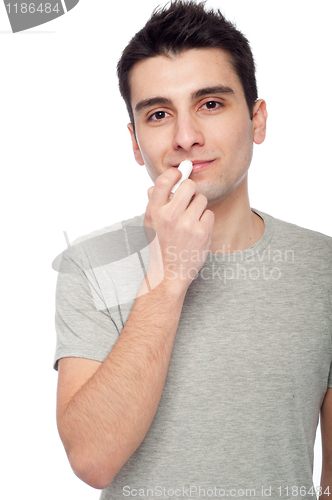 Image of Young man applying lip balm