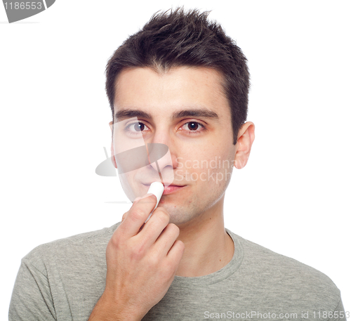 Image of Young man applying lip balm