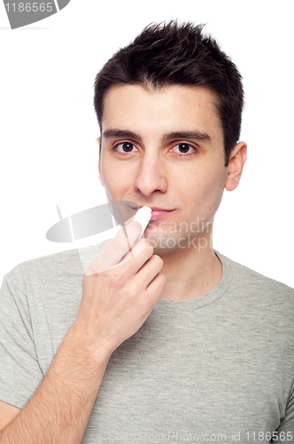 Image of Young man applying lip balm