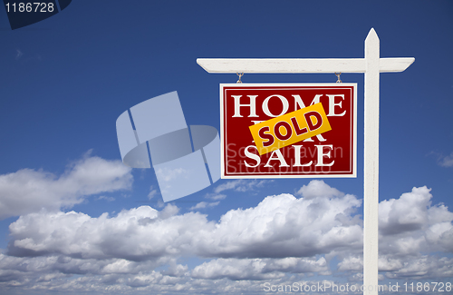 Image of Red Sold Home For Sale Real Estate Sign Over Clouds and Sky