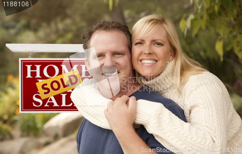 Image of Happy Couple in Front of Sold Real Estate Sign