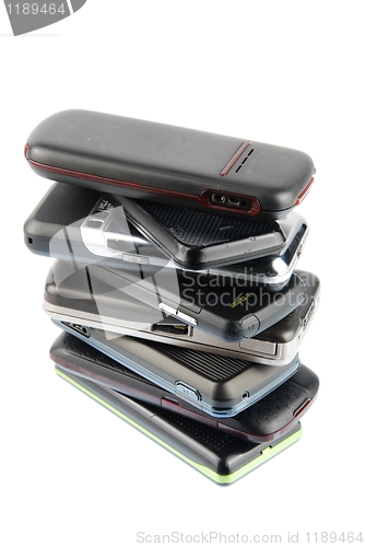 Image of Heap of modern mobile phones on white