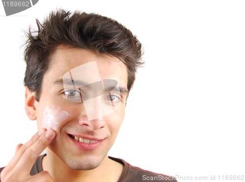 Image of Smiling man applying face cream