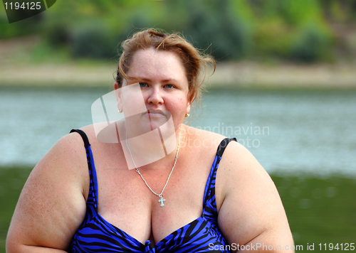 Image of plump woman sitting near river