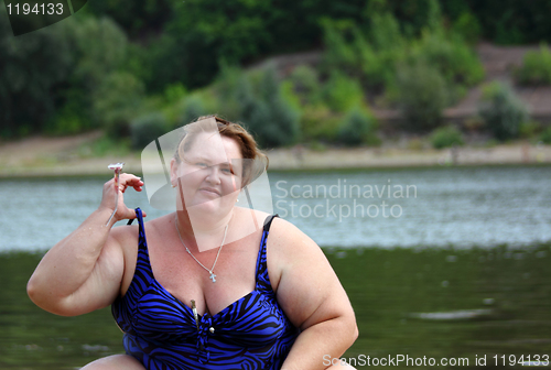Image of plump woman sitting near river