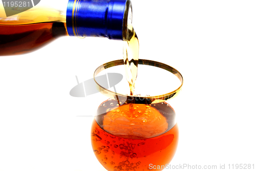 Image of Bottleneck filling a glass with brown liquid
