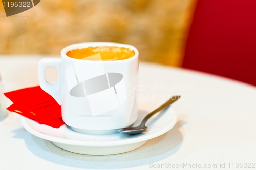 Image of white cup of cappuccino coffee on light background with spoon