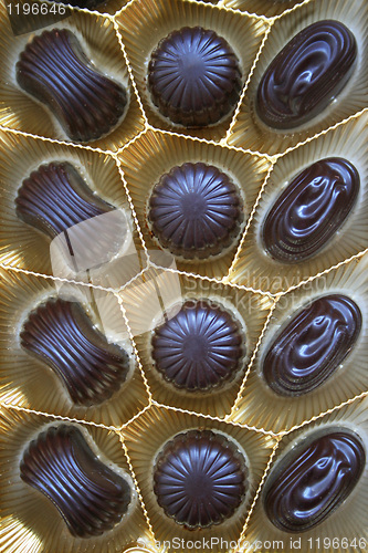 Image of Delicious dark chocolate sweets in box as background