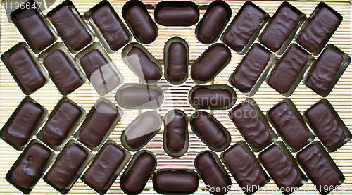 Image of Delicious dark chocolate sweets in golden box as background