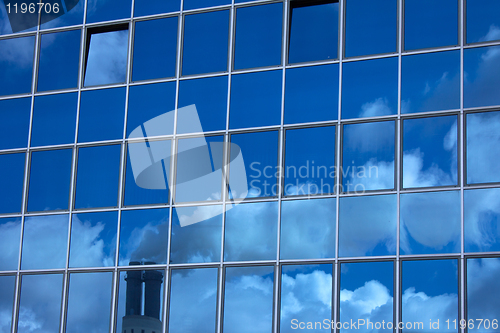 Image of Glass facade with a reflection of a smoky chimney