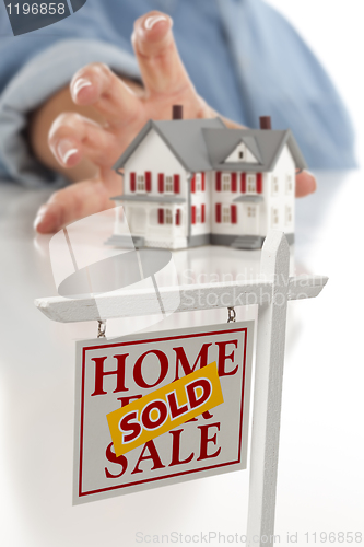 Image of Sold Real Estate Sign in Front, Woman Reaching for House