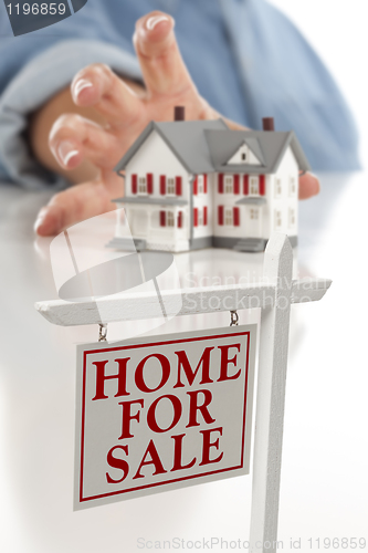 Image of Real Estate Sign in Front of Woman Reaching for House