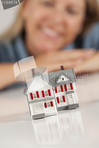 Image of Smiling Woman Behind Model House on a White Surface