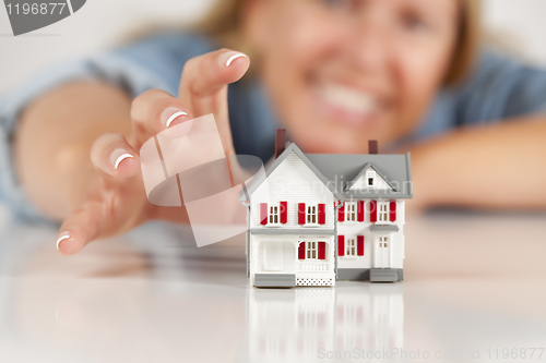 Image of Smiling Woman Reaching for Model House on White