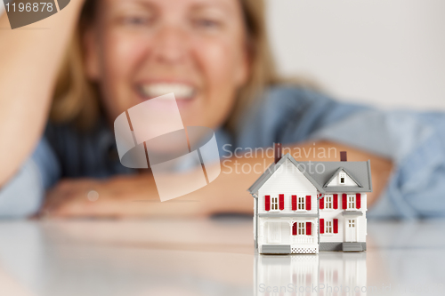 Image of Smiling Woman Behind Model House on a White Surface