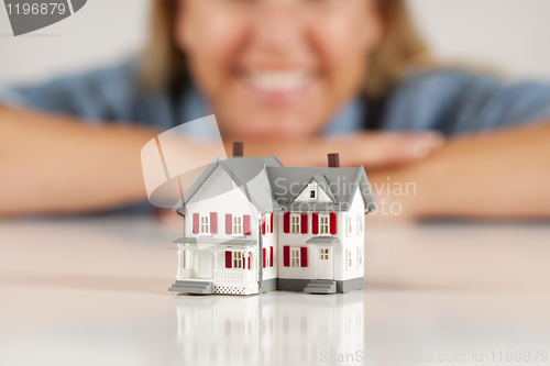 Image of Smiling Woman Behind Model House on a White Surface