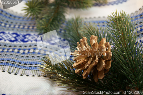 Image of Green spruce boughs and a gilden cone in a traditional embroider