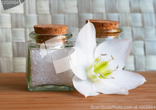 Image of Bottles of sea salt and oil with white flower